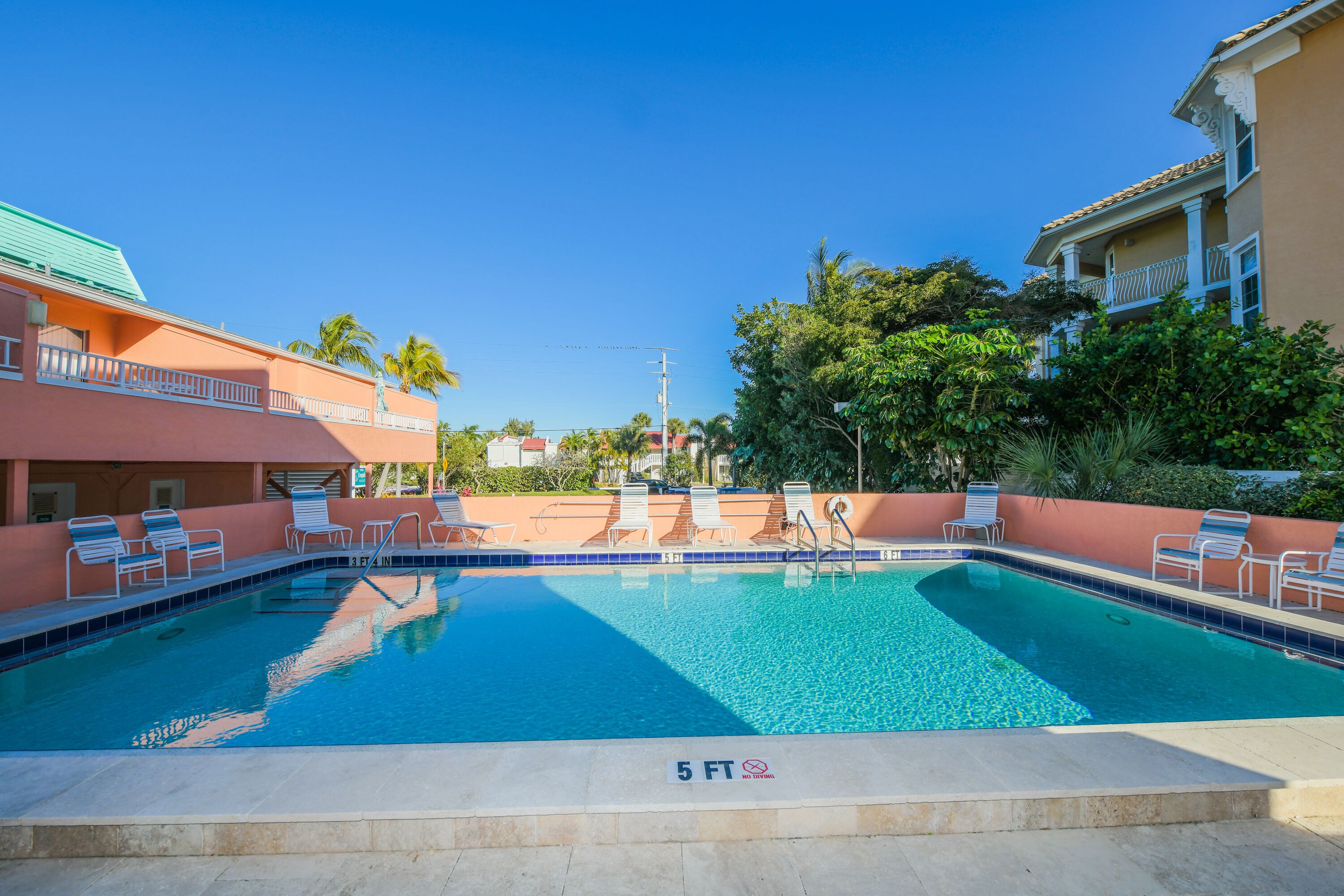 A swimming pool with lounge chairs and a 5 ft depth marker.