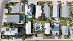 An aerial view of a residential area with multiple houses, each with a swimming pool and surrounded by palm trees. - Cozy Family Duplex with Pool! Close to the Gulf Beaches (Anna Maria)