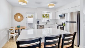 A modern kitchen with white cabinetry, a large island, and stainless steel appliances. - Cozy Family Duplex with Pool! Close to the Gulf Beaches (Anna Maria)