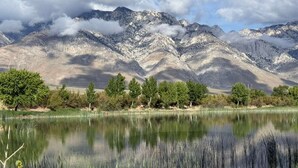 Paesaggio montano con un lago in primo piano e cielo sereno.