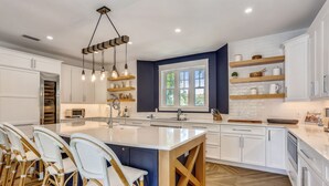 Een moderne keuken met een groot eiland, witte kasten en een houten vloer.