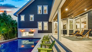 Een modern huis met een zwembad, buitenmeubels en een overdekt terras.