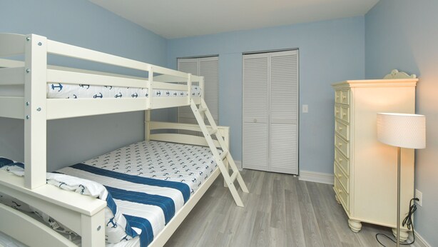 A bunk bed room with a dresser and a lamp. - Beachfront Condo with Amazing Views and Pool! Near Bridge Street! (Bradenton Beach)