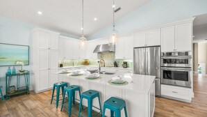 A modern kitchen with white cabinetry, stainless steel appliances, and a central island with bar stools.