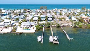 An aerial view of a coastal residential area with houses, a dock, and boats. - Bayblue — Spacious 6BR Retreat with Pool and Dock! (Bradenton Beach)