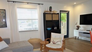 A living room with a sofa, a chair, a small table, a television, and a wooden floor. - Bungalow with Private Heated Pool! One Block to Beach! - Salty Dog (Holmes Beach)