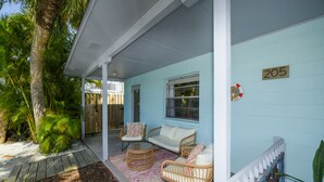 A light blue building with the number 205, a covered porch with wicker furniture, and a palm tree. - Bungalow with Private Heated Pool! One Block to Beach! - Salty Dog (Holmes Beach)