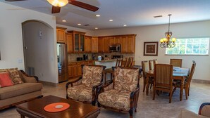A spacious living room with a sofa, two armchairs, a coffee table, and a dining area with a table and chairs.