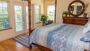 A bedroom with a large bed, a ceiling fan, a wooden dresser, a mirror, and a door with a 'Relax' sign.