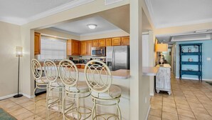 Una cocina moderna con armarios de madera, electrodomésticos de acero inoxidable y una zona de bar con sillas de metal.