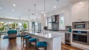 A modern kitchen with a large island, stainless steel appliances, and a view to the outdoors. - Canal front home with Incredible Rooftop Views and Pool with Spa - Aqua Bay (Holmes Beach)