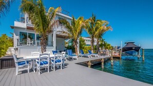 A modern waterfront property with a wooden deck, lounge chairs, and a pool area. - Canal front home with Incredible Rooftop Views and Pool with Spa - Aqua Bay (Holmes Beach)