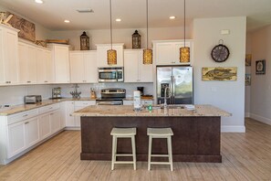 Enjoy cooking in this well-equipped kitchen with a central island, stainless steel appliances, and a large island sink.