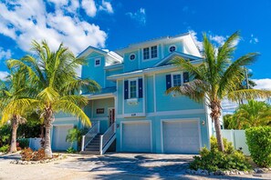 Stunning two-story residence with a front entrance, staircase, and garage doors, surrounded by palm trees.