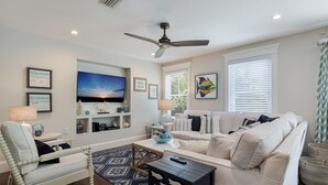A living room with a sofa, armchair, TV, and decorative items. - Large Private Duplex, Heated Pool and Spa! (Holmes Beach)