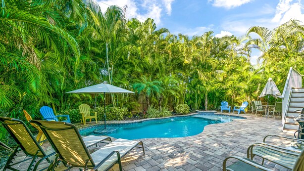 A swimming pool surrounded by lush greenery and outdoor seating.