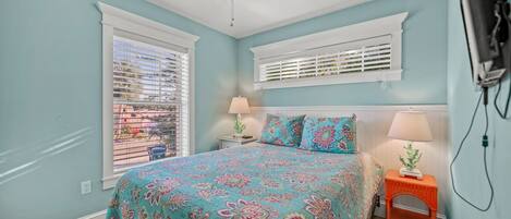 A bedroom with a bed, two bedside tables, a ceiling fan, and a window with blinds.