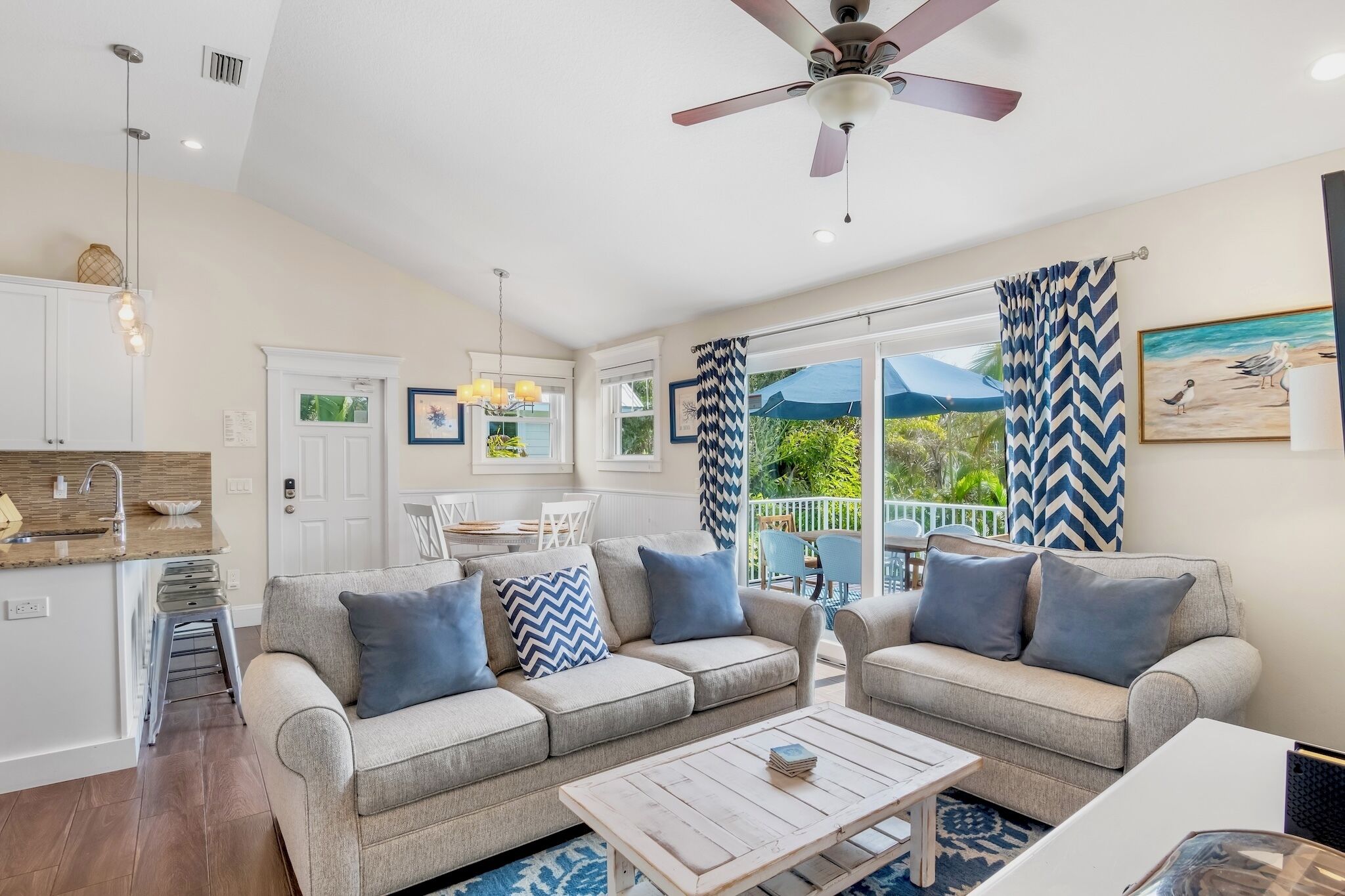 A modern living room with two sofas, a coffee table, and a ceiling fan.