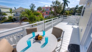A round table with four chairs on a balcony, a fruit bowl, and blue glassware.