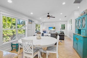 A spacious living area with a round white table, comfortable seating, a ceiling fan, and a television. - Pet Friendly Private Duplex. Fenced Yard with Private Pool Short Walk to Beach (Holmes Beach)
