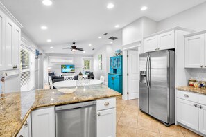 A modern kitchen with white cabinetry, a stainless steel refrigerator, and a granite countertop. - Pet Friendly Private Duplex. Fenced Yard with Private Pool Short Walk to Beach (Holmes Beach)