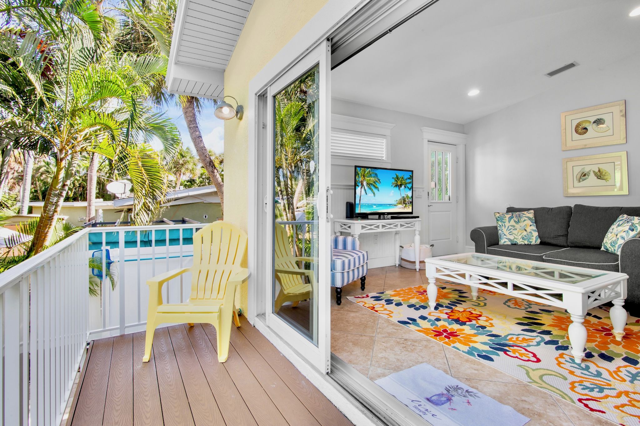 A balcony with a pool, a television, a sofa, and a coffee table.