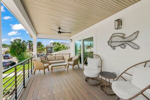 Relax in this serene outdoor space with a comfortable sofa, wicker chairs, and a decorative fish wall art piece.