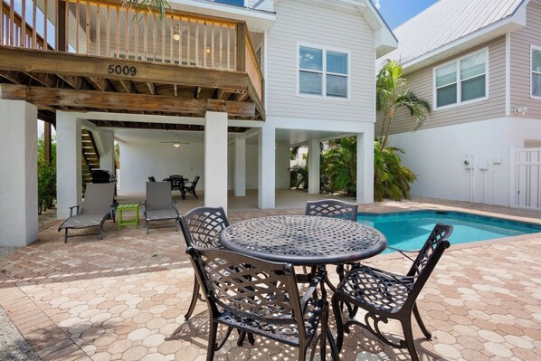 A covered patio area with a pool, outdoor seating, and a wooden deck.