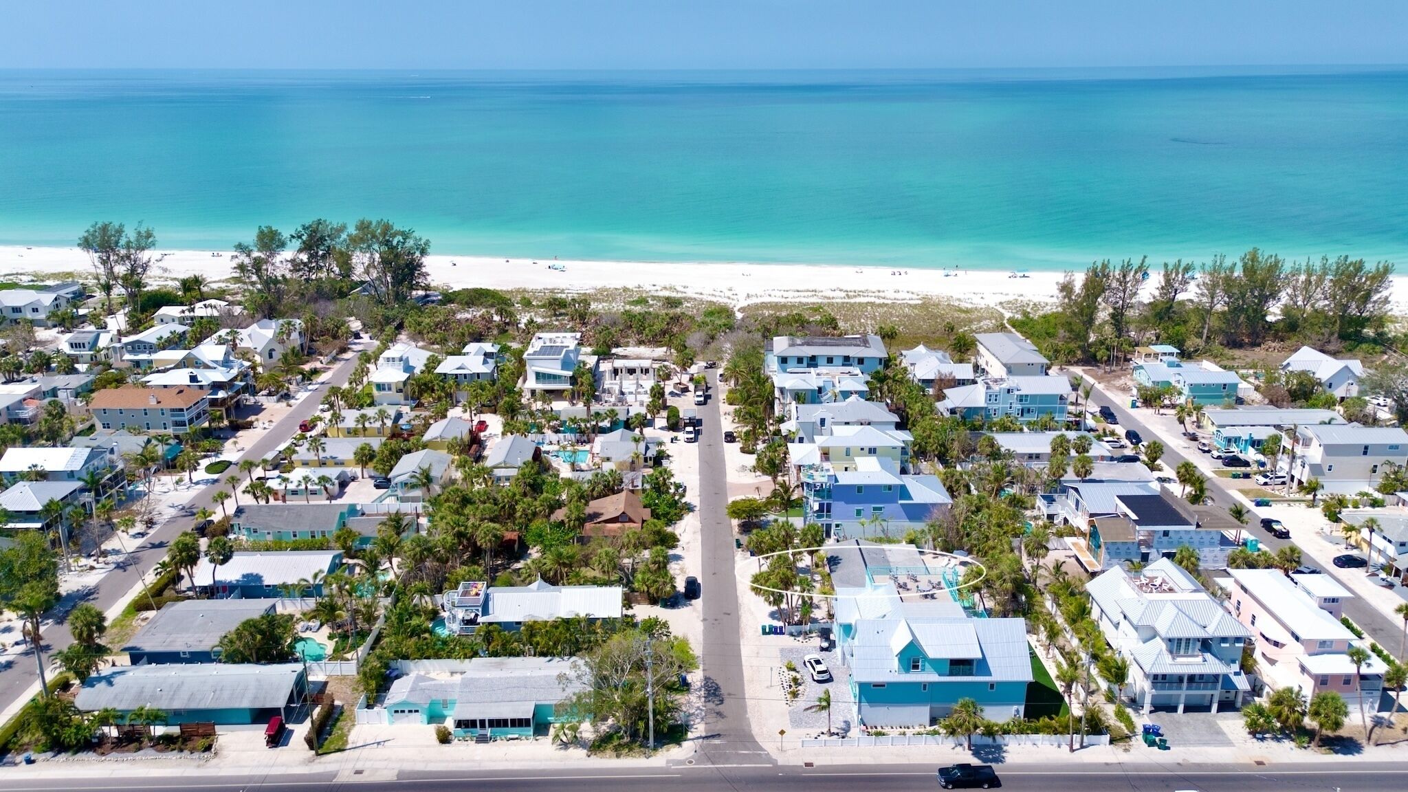 A coastal residential area with houses, a beach, and a clear view of the ocean.