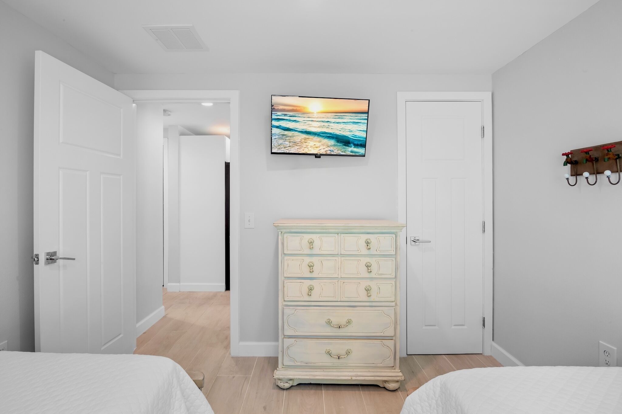 Un dormitorio con dos camas, un aparador y un televisor en la pared.