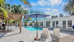 A poolside area with a wooden pergola, lounge chairs, and a table. - Private Duplex with Beautiful Updates and Heated Pool! 1 Minute from the Beach! (Anna Maria)