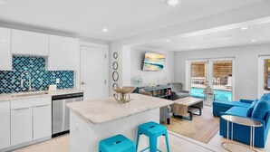 A modern kitchen with white cabinets, a stainless steel dishwasher, and a blue tiled backsplash. - Private Duplex with Beautiful Updates and Heated Pool! 1 Minute from the Beach! (Anna Maria)