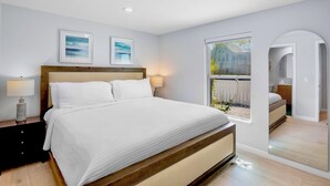 Une chambre à coucher avec un grand lit, deux tables de chevet, une fenêtre donnant sur un beau paysage et un miroir.