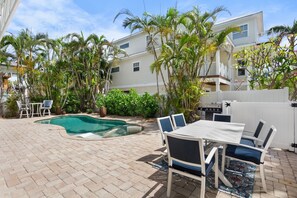 Un jardin avec une piscine, du mobilier de jardin et une clôture blanche.