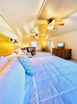 Um quarto com cama, penteadeira de madeira, escrivaninha e cadeira.