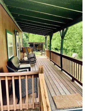 Um deck coberto com móveis de exterior e vista para o verde ao redor.