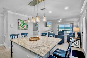 A modern kitchen with a central island, blue chairs, and a dining table.