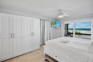 Une chambre avec un grand lit, une armoire blanche et une vue sur la plage.