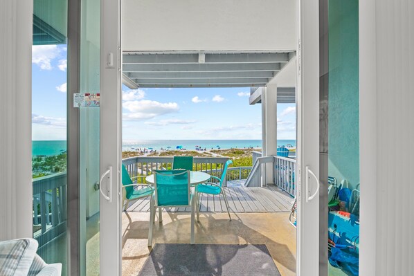 Enjoy the ocean view from this spacious balcony with a clear view of the beach, featuring two comfortable chairs and a table.