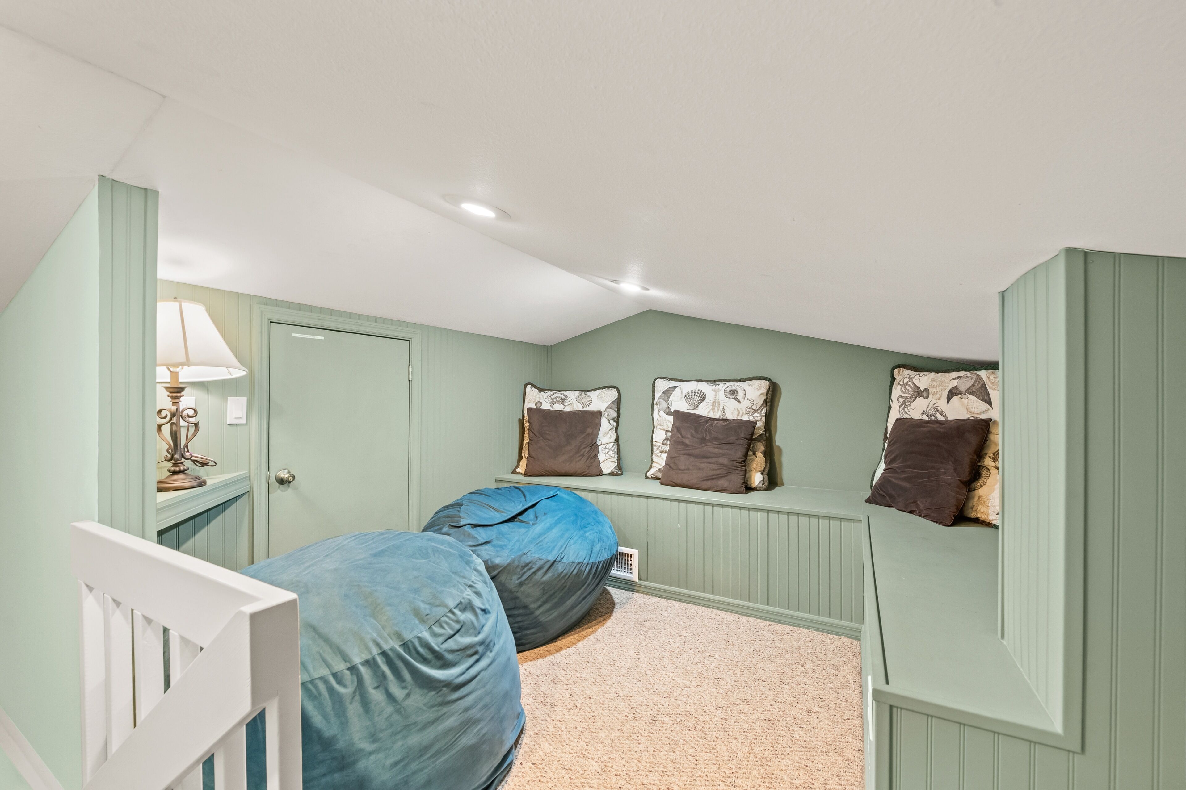 A bedroom with two bean bags, a bed, a dresser, and a lamp.