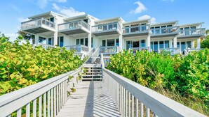 Un hôtel en bord de mer, composé de plusieurs étages, doté de balcons et d’une passerelle en bois menant à l’entrée.