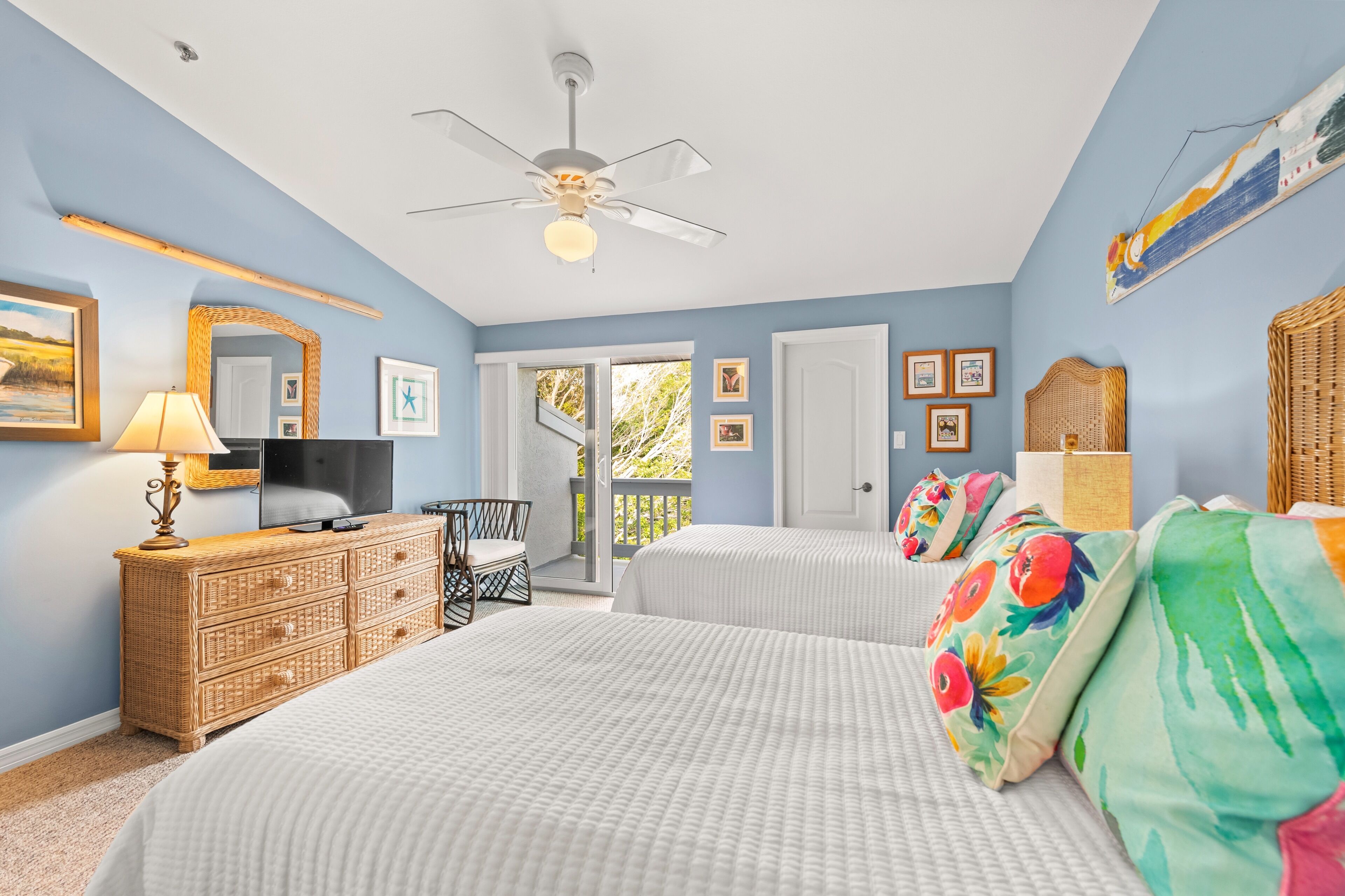 A bedroom with two beds, a TV, a dresser, and a ceiling fan.