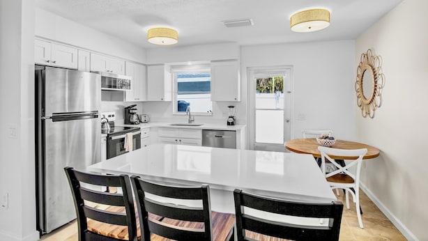 A modern kitchen with white cabinetry, stainless steel appliances, and a large island with seating.