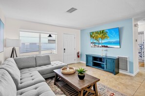 Relax in this spacious living room with a large sofa, coffee table, and entertainment unit, offering a view of the outdoors.