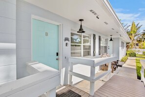 Guests can enjoy a shaded outdoor space on the covered porch with a wooden deck.
