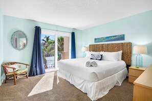 A hotel room with a bed, a chair, a nightstand, a lamp, a window with curtains, and a painting on the wall.