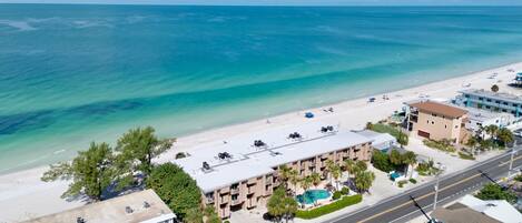 Un hotel frente a la playa con piscina, acceso directo a la orilla y una carretera en primer plano.