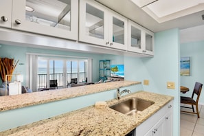 A modern kitchen with granite countertops, a stainless steel sink, and white cabinetry.