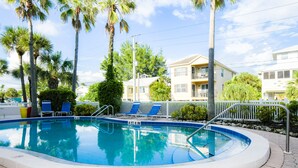 A 3-foot pool with blue tiles, surrounded by palm trees and a brick walkway.