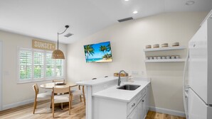 A modern kitchen with white cabinetry, a built-in island with a sink, and a breakfast bar. - Beach Home with Pool and Gas Grill! 2 min walk to Beach! (Holmes Beach)